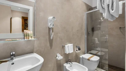 Bagno moderno con lavabo, bidet, wc, doccia e asciugamani bianchi