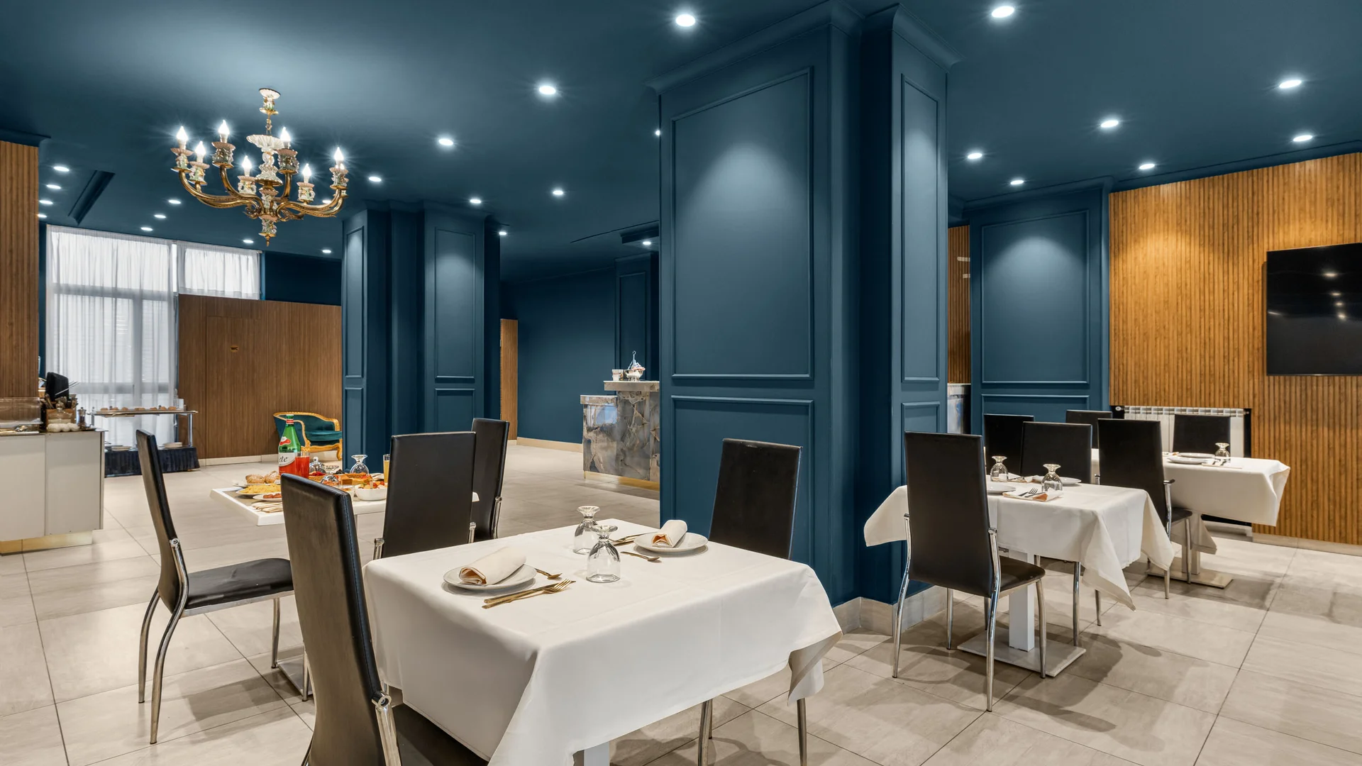 Sala da pranzo elegante con pareti blu e tavoli apparecchiati con tovaglie bianche