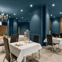 Sala da pranzo elegante con pareti blu e tavoli apparecchiati con tovaglie bianche