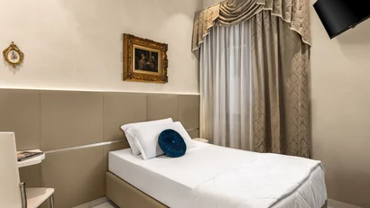Camera singola elegante con letto bianco e tenda decorativa beige