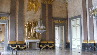 Interno di una sala storica con statue dorate e lampadario di cristallo