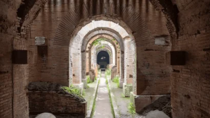Corridoio antico con archi in pietra e vegetazione verde