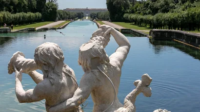 Statua di due figure mitologiche vicino a un lungo canale d'acqua in un giardino