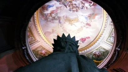 Statua con corona vista dal basso e soffitto affrescato decorato