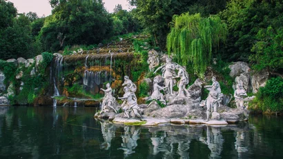 Statue di figure mitologiche vicino a una cascata in un giardino verde