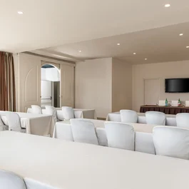 Sala conferenze con sedie bianche e tavoli coperti da tovaglie bianche