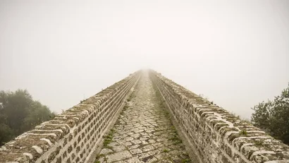 Sentiero in pietra con muri laterali che scompare nella nebbia