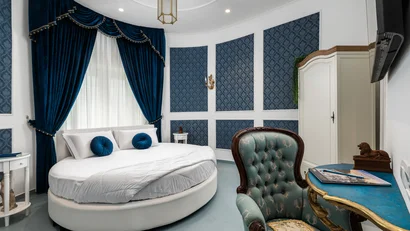 Camera da letto elegante con letto rotondo e tende blu scuro