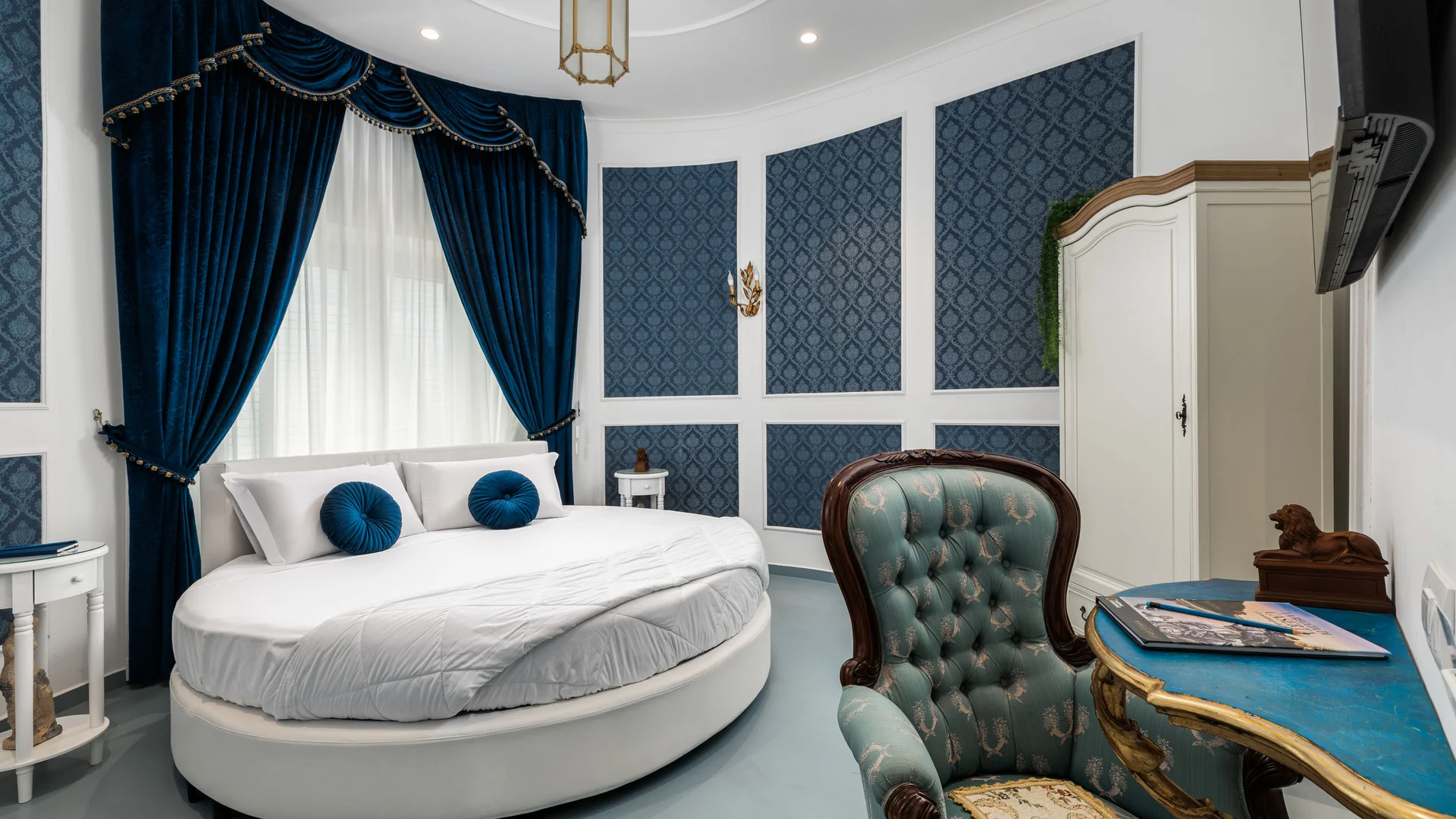 Camera da letto elegante con letto rotondo e tende blu scuro
