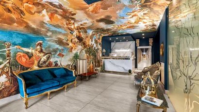 Reception di hotel con divano blu, affreschi sul soffitto e pareti