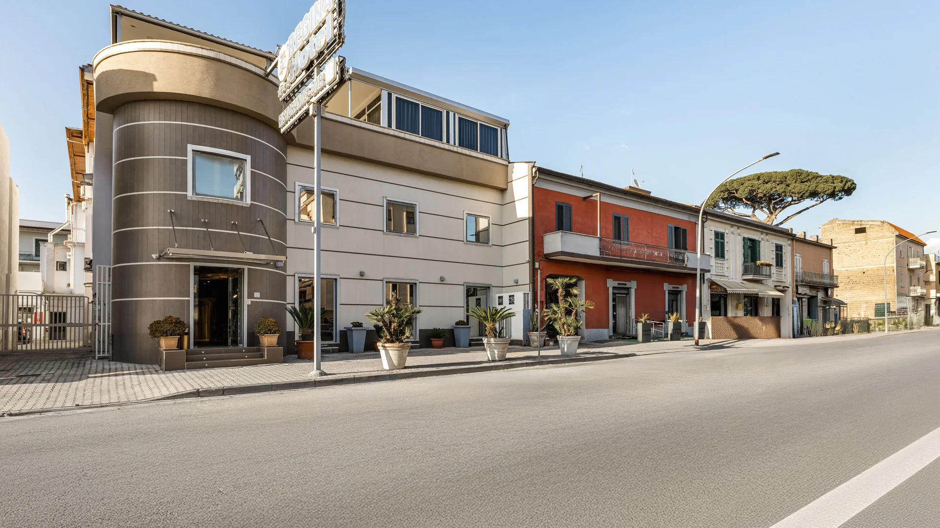 Facciata moderna di un hotel con piante in vaso lungo la strada