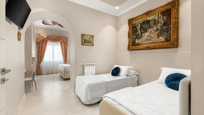 Camera d'albergo con due letti singoli, dipinti alle pareti e TV a schermo piatto