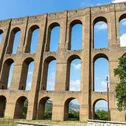 Antico acquedotto in pietra con archi sotto un cielo azzurro