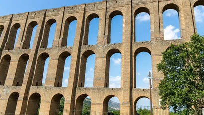 Antico acquedotto in pietra con archi sotto un cielo azzurro