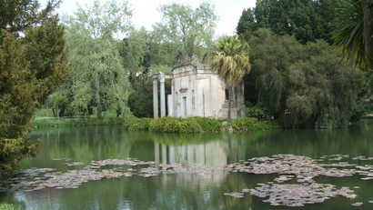 Tempietto antico su un'isola in un lago con ninfee e alberi verdi