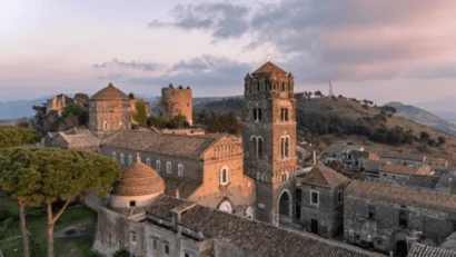 Veduta di un antico complesso di edifici in pietra con torri e cupole al tramonto